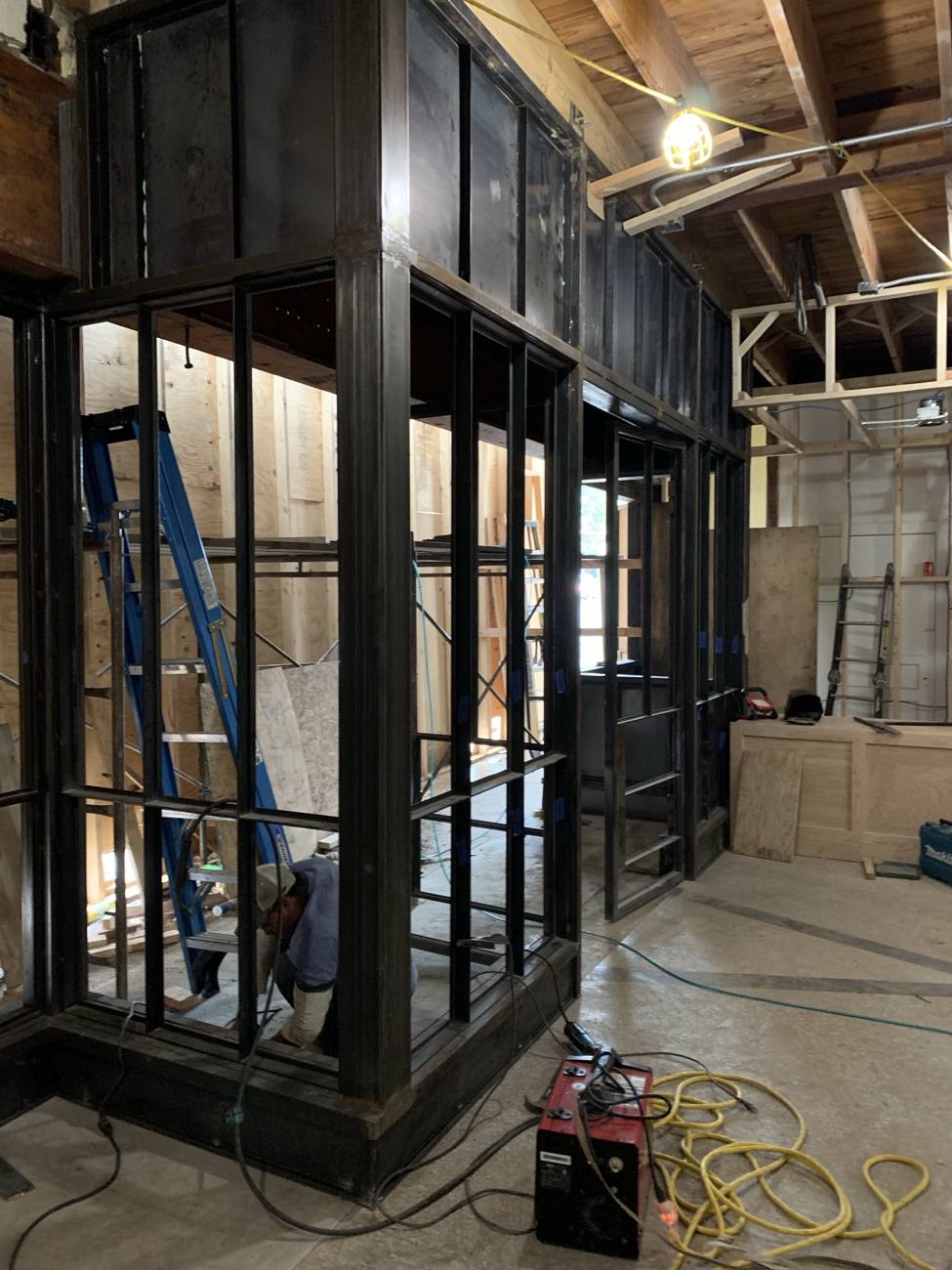 Installer welding a two story steel display enclosure on site