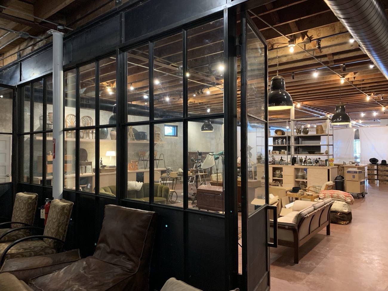 Black steel and glass partition with a hinged door inside a retail showroom